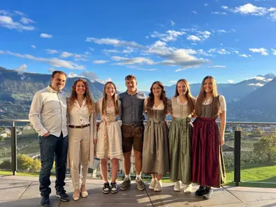 a group of people posing for a picture in front of mountains at Hotel Lechner in Tirolo