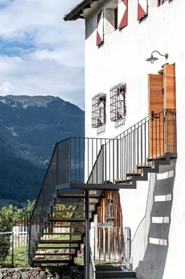 a staircase on the side of a building with mountains in the background at Ansitz Fonteklaus in Chiusa