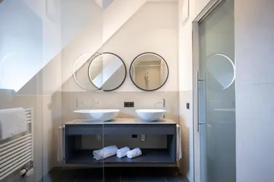a bathroom with two sinks and two mirrors at Ansitz Fonteklaus in Chiusa