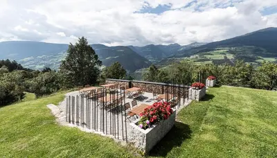 a group of tables and chairs on a hill with mountains at Ansitz Fonteklaus in Chiusa