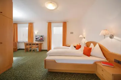 a hotel room with two beds and a desk at Garni Unterhaslerhof in Merano