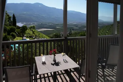 a table on a balcony with a view of the mountains at Apparthotel Calma in Cermes
