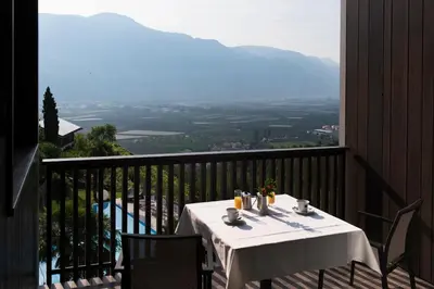 a table on a balcony with a view of a valley at Apparthotel Calma in Cermes