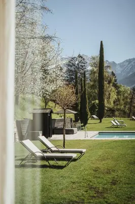 a couple of lounge chairs in the grass by a pool at Hotel KÜGLERHOF in Tirolo