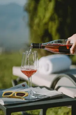 a person pouring wine into a wine glass at Hotel KÜGLERHOF in Tirolo