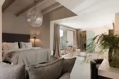 a bedroom with a bed and chairs in a room at Hotel KÜGLERHOF in Tirolo