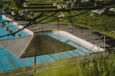 an overhead view of a swimming pool with an umbrella at Hotel KÜGLERHOF in Tirolo