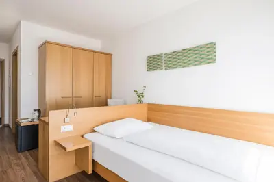 a bedroom with a white bed and a wooden cabinet at Residence Aqualis in Marlengo