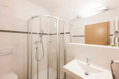 a white bathroom with a shower and a sink at Residence Aqualis in Marlengo