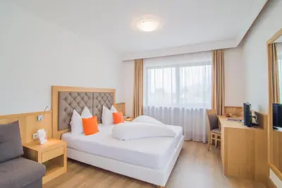 a bedroom with a bed and a couch and a television at Hotel Sonnenhof in Lana