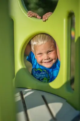 a young boy is smiling in a play structure at Hotel Sonnenhof in Lana