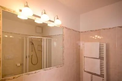 a bathroom with a shower and a large mirror at Hotel Sonnenhof in Lana
