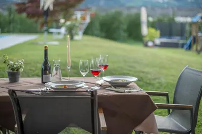 a table with a bottle of wine and glasses on it at Hotel Sonnenhof in Lana