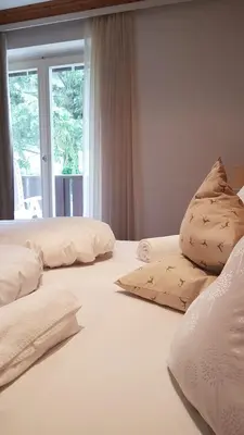 three pillows on a bed in a room with a window at Pension Lärchenhof in Naturno