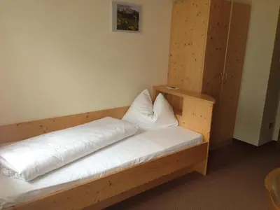 a wooden bed with white sheets and pillows on it at Pension Lärchenhof in Naturno