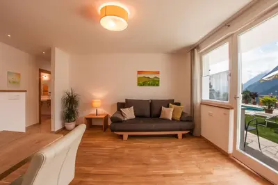 a living room with a couch and a large window at Pension Verdinserhöhe in Schenna
