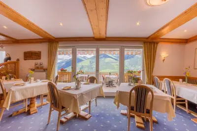 a dining room with tables and chairs and a large window at Pension Verdinserhöhe in Schenna