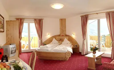 a hotel room with a bed with white pillows at Pension Verdinserhöhe in Schenna