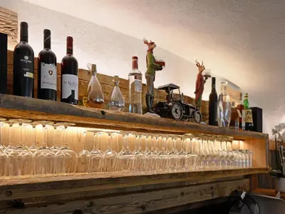 a row of wine glasses on a shelf with wine bottles at Apart Residence Rautal ***S in San Vigilio Di Marebbe