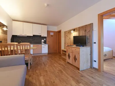 a room with a kitchen and a living room with a television at Apart Residence Rautal ***S in San Vigilio Di Marebbe