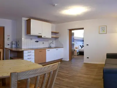 a kitchen and living room with a table and a dining room at Apart Residence Rautal ***S in San Vigilio Di Marebbe