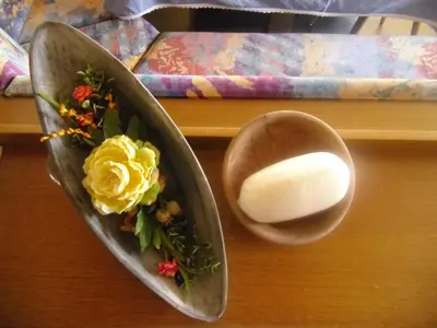 a wooden table with a plate with a bowl with flowers at Garni Margherita in Corvara in Badia