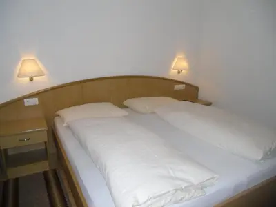 a bed with two white pillows on it with two lights at Garni Margherita in Corvara in Badia