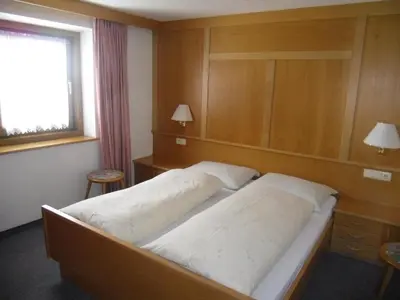 a bedroom with two beds and a window at Garni Margherita in Corvara in Badia