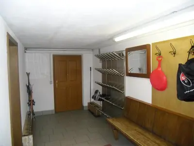 a room with a bench and a wall with weapons at Garni Margherita in Corvara in Badia