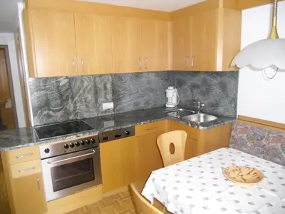 a kitchen with wooden cabinets and a table with a sink at Garni Margherita in Corvara in Badia