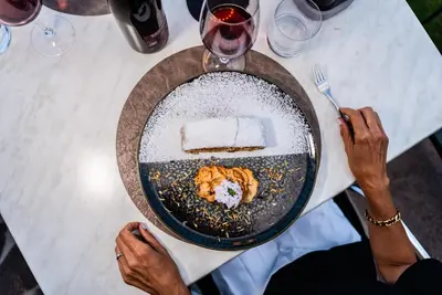 a person holding a plate of food on a table at Hotel Tannhof in Caldaro