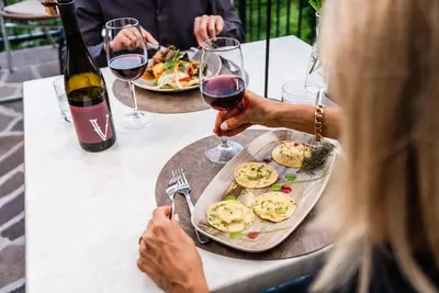 a woman sitting at a table with a plate of food and wine at Hotel Tannhof in Caldaro