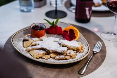 a plate of food with powdered sugar and fruit on a table at Hotel Tannhof in Caldaro