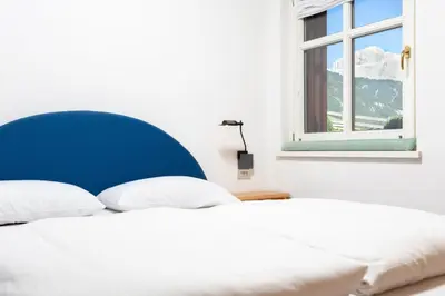 a white bed with a blue headboard and a window at Kristiania in Campitello