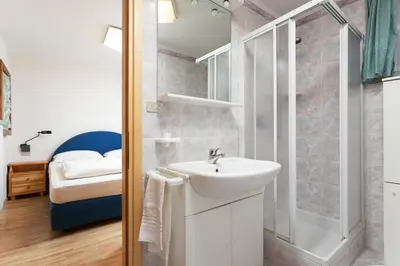 a bathroom with a sink and a shower and a bed at Kristiania in Campitello