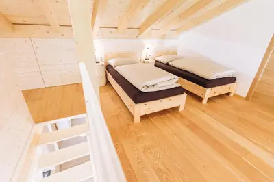 two beds in a room with wooden floors at Baumgartnerhof MÜLLER THURGAU in Cortaccia