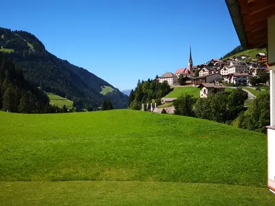 a green hill with houses and a village on it at Artitsch in Santa Cristina in Val Gardena