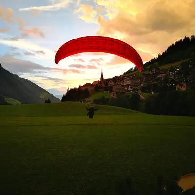 a person flying a red parachute over a field at Artitsch in Santa Cristina in Val Gardena