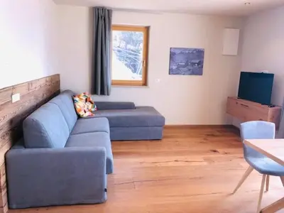 a living room with a blue couch and a television at Ferienwohnungen Oberweier in Merano