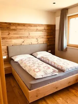 a bed in a room with a wooden wall at Ferienwohnungen Oberweier in Merano