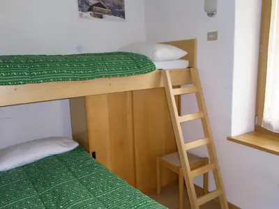 a room with two bunk beds and a ladder at Casa Elisa in Pozza di Fassa