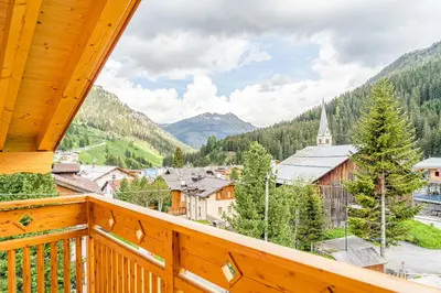 a balcony with a view of a town and a church at Blizzard apartments in Arabba