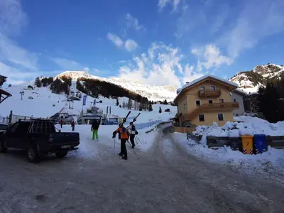 a group of people on skis in the snow near a ski lodge at Blizzard apartments in Arabba