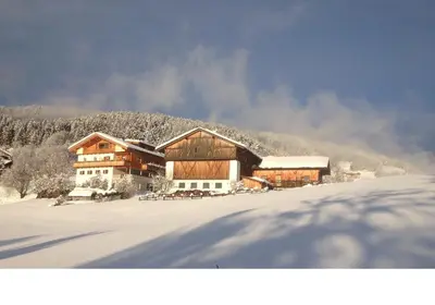 a large wooden building with snow on the ground at Gasleidhof in Funes