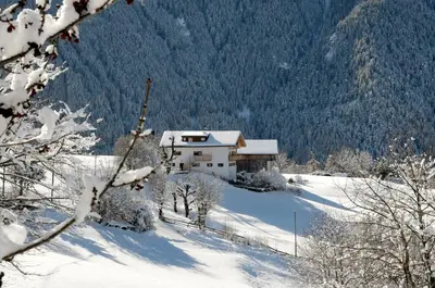 a house on a snow covered hill with a building at Gasleidhof in Funes