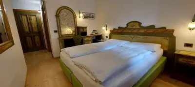 a bedroom with a large bed with a wooden headboard at Garnì Stella Alpina in Canazei