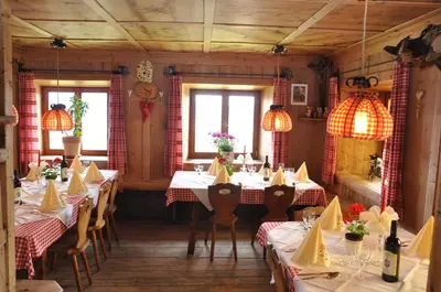 a restaurant with tables with red and white tablecloths at Berggasthof Häusler in San Lorenzo di Sebato
