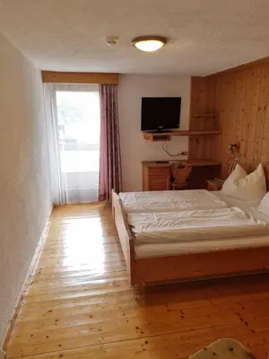 a bedroom with a large bed and a television at Berggasthof Häusler in San Lorenzo di Sebato