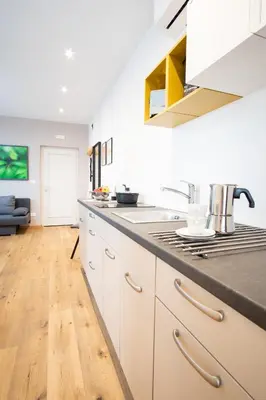 a kitchen with white cabinets and a wooden floor at Apartment Hanna in Merano