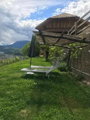 a chair and an umbrella in the grass at Kristplonerhof in Bolzano